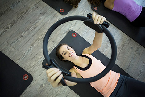 Mujer obteniendo beneficios del Pilates mediante la práctica de ejercicios con un aro.